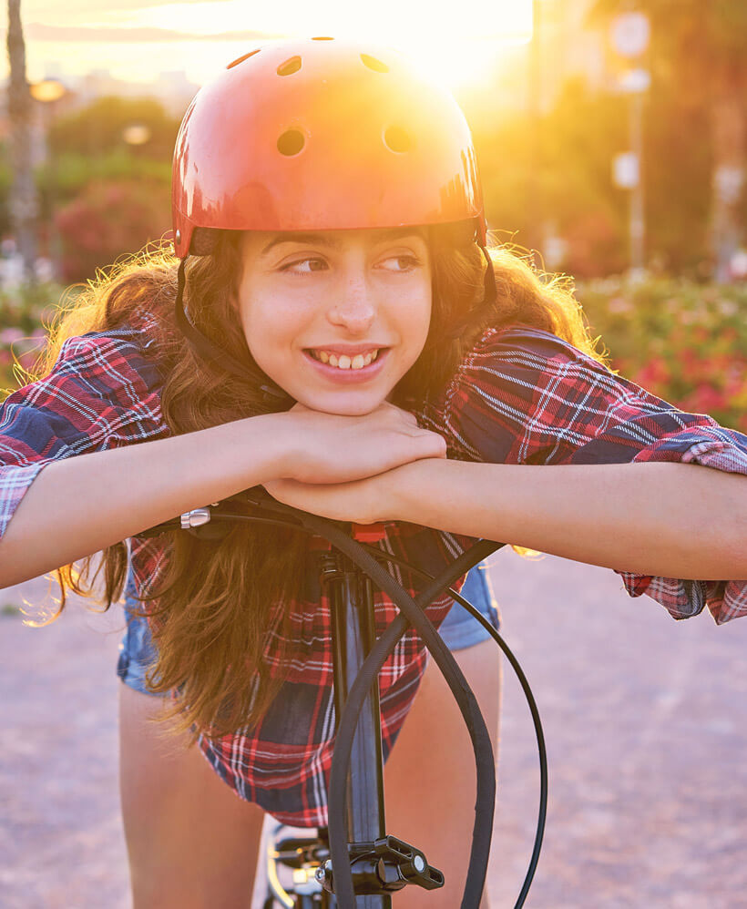 girl on bike smiles, revealing her comfortable braces for teens