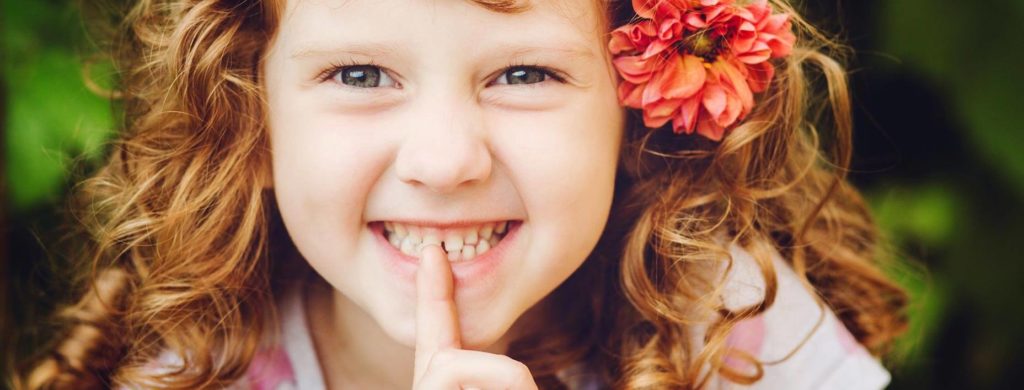 Girl pointing at her extra teeth growing in her gums