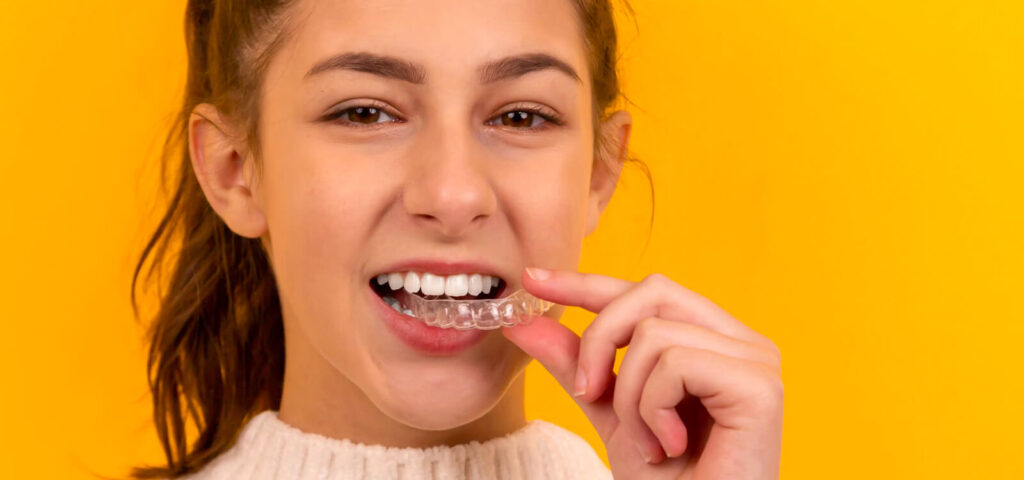 teen girl holds invisalign tray while learning the Invisalign process step by step