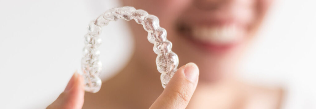 adult shows aligner while learning Invisalign dos and don'ts