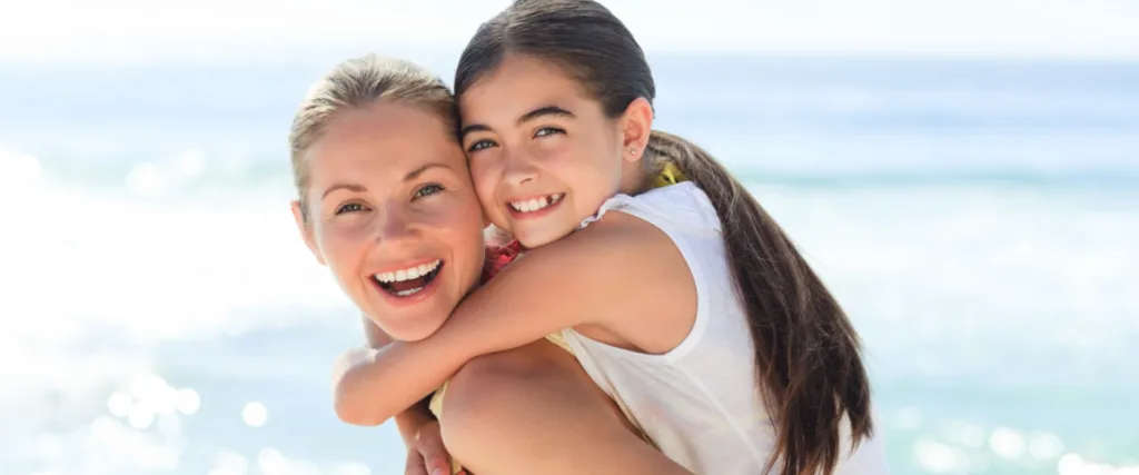 mother and daughter piggyback on beach and talk about smiledirectclub lawsuit