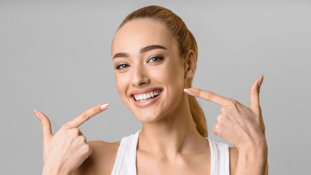 adult points to smile after using payment plan for Invisalign