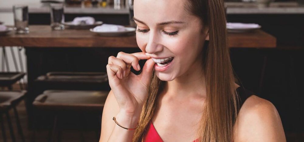 Young woman puts in her invisalign tray on her first day with invisalign