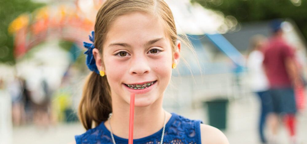 teen learns about flossing with braces while sipping drink